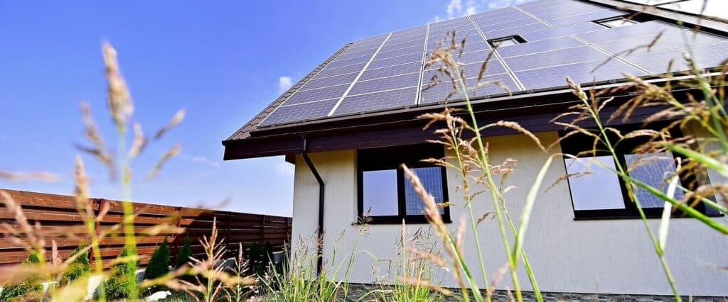 Panneaux solaires sur toit de maison : énergie durable Maison moderne avec panneaux solaires photovoltaïques sur le toit sous un ciel bleu dégagé.